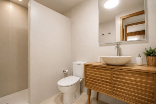 Baño moderno con vanidad de madera, lavamanos de piedra y ducha en el apartamento Riurau Home de Calpe