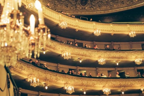 Interior de gran teatro histórico con balcones dorados ornamentados, candelabros y público en Lyon