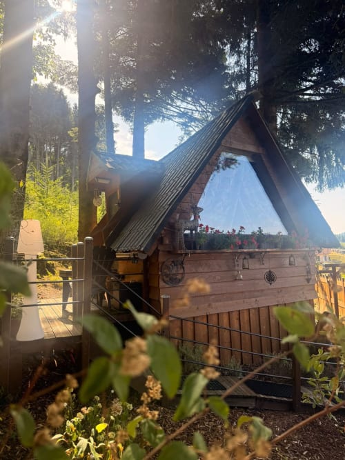 Cabane en bois en forme de A nichée dans la forêt aux Cabanes des Marchous, Granges-Aumontzey