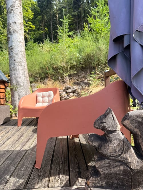 Salon de terrasse aux Cabanes des Marchous avec chaise corail, vue sur la forêt