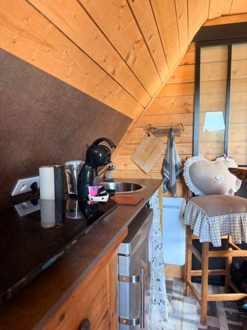Cuisine chaleureuse avec machine à espresso, plafond en bois et vue sur les montagnes aux Cabanes des Marchous