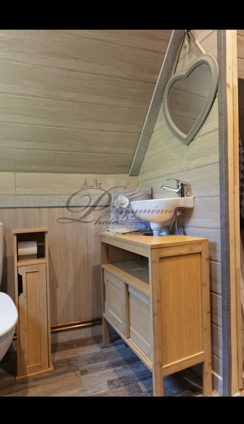 Salle de bain en bois de la cabane Marmotte avec lavabo, miroir et toilettes aux Cabanes des Marchous