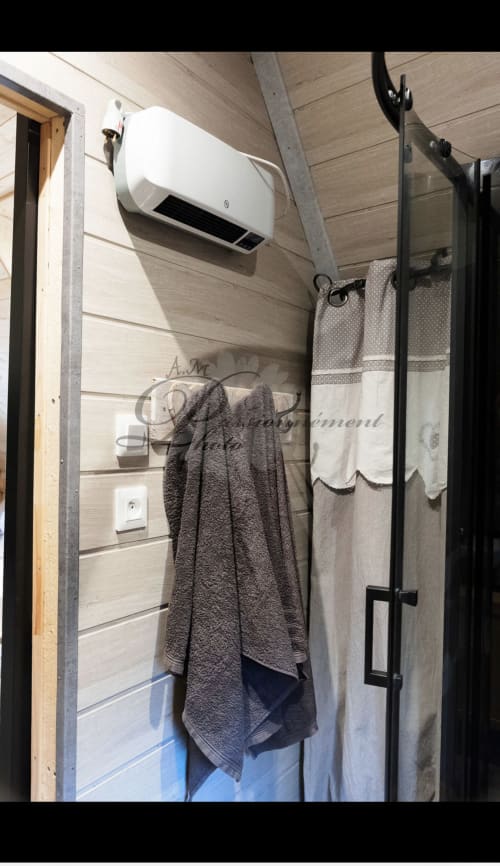 Salle de bain moderne à la Cabane Marmotte avec radiateur mural, porte-serviettes foncé et panneaux de bois