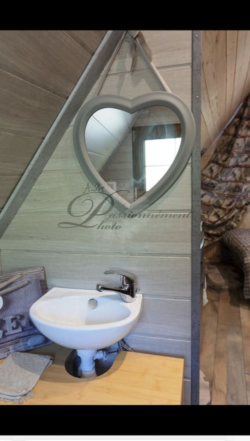 Miroir en forme de cœur au-dessus d'un lavabo blanc sur piédestal dans la salle de bain rustique du gîte Les Cabanes des Marchous, Granges-Aumontzey