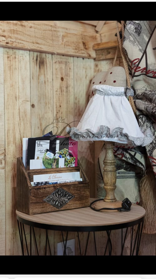 Petite table de nuit rustique en bois dans le chalet Cabane Marmotte, ornée d'une lampe, d'une boîte de rangement en bois et de produits spa