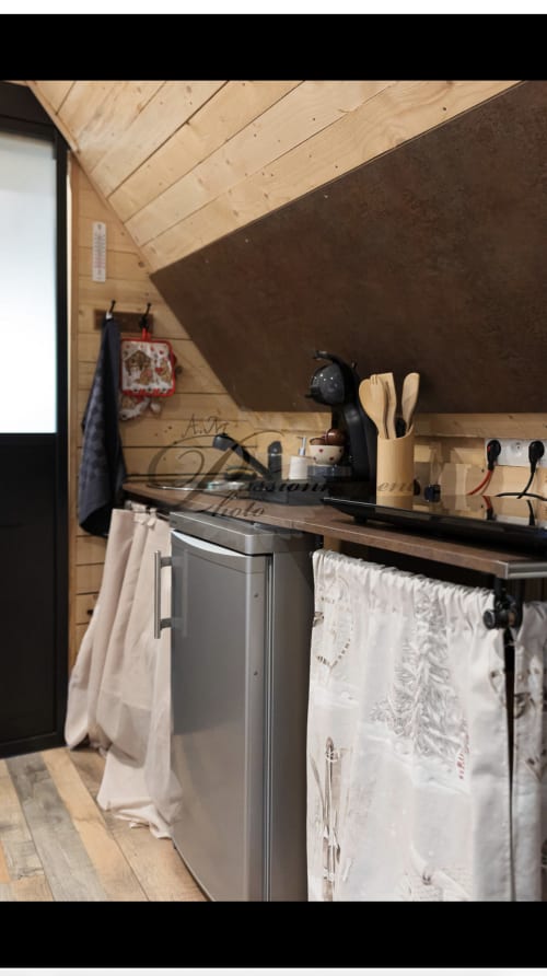 Kitchenette compacte de la Cabane Marmotte aux Cabanes des Marchous, avec murs en bois, évier en acier inoxydable et