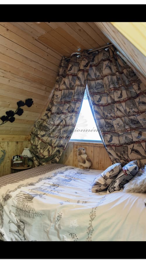 Chambre cosy dans une cabane en bois avec rideaux motifs et vue sur la montagne aux Cabanes des Marchous, Granges-Aumontzey