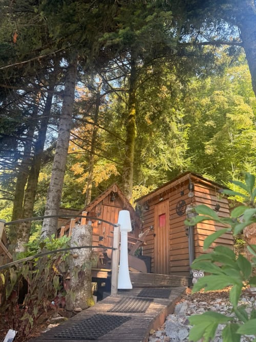Petite maison en bois nichée parmi les grands arbres aux Cabanes des Marchous, gîte insolite en France, à Granges-Aumontzey