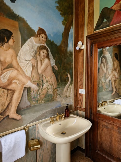 Luxurious bathroom at Veneto Villa with pedestal sink, gold fixtures, and classical frescoed walls featuring mythological