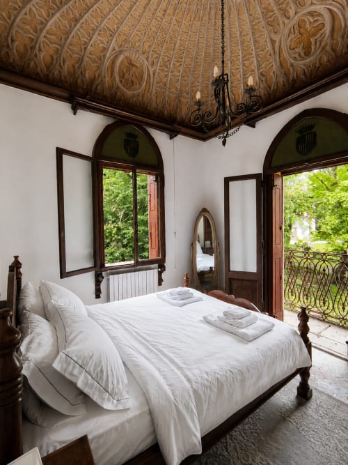 Elegant bedroom at Veneto Villa Lake House in Sant'Agostino with ornate ceiling, arched doors, lake views, and white bedding