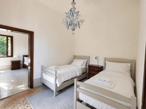 Twin bedroom in Lake House villa at Veneto Villa, Sant'Agostino with elegant twin beds, chandelier, and lake views