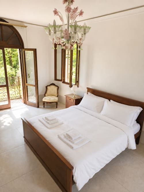 Luxurious bedroom with wooden bed, ornate chandelier, and lake views at Veneto Villa in Sant'Agostino, Italy