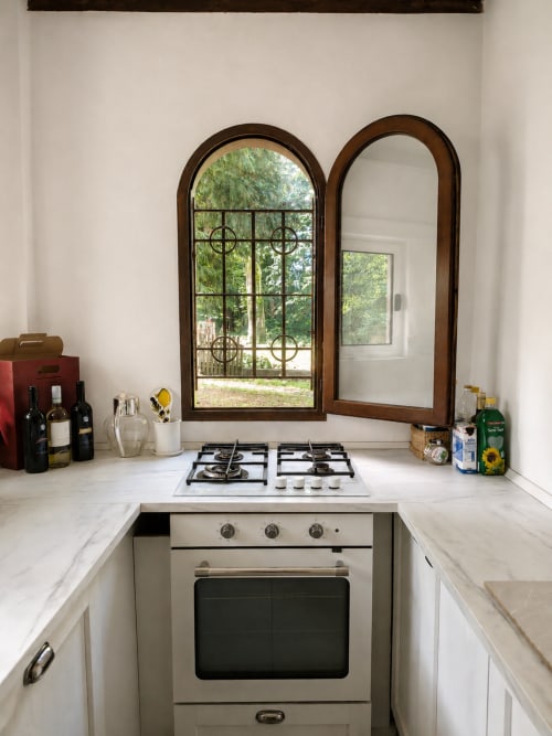 Compact kitchen at Veneto Villa Lake House with gas cooktop, white marble counters, and arched wooden-framed windows
