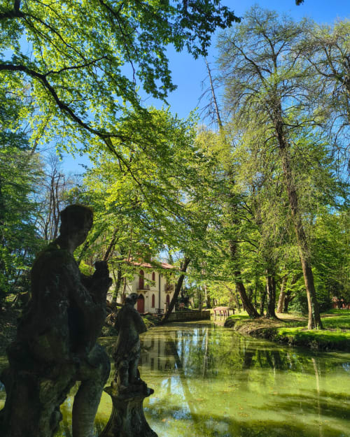 Veneto Villa villa garden with stone statues, canal, and chapel surrounded by lush trees