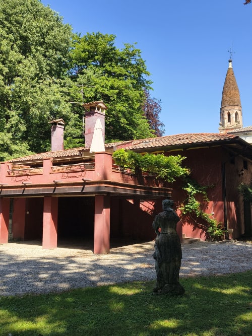 Red-brick Garden Loft courtyard at Veneto Villa with bell tower, lush greenery, and statue in Sant'Agostino
