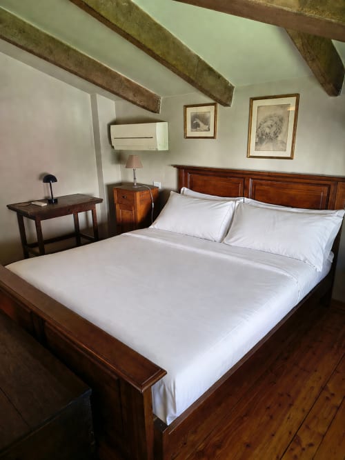 Spacious bedroom in Garden Loft at Veneto Villa with wooden beams, queen bed, desk, nightstand, and framed artwork in