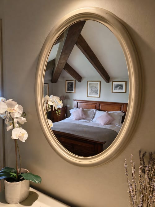 Oval mirror reflecting bedroom with wooden beams at Veneto Villa garden loft in Sant'Agostino, Italy