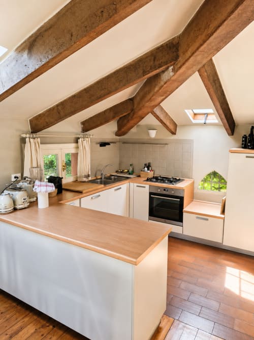 Garden Loft kitchen at Veneto Villa with exposed wooden beams, white cabinetry, wood countertops, and garden views
