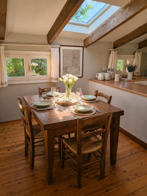 Bright dining room in Garden Loft apartment at Veneto Villa with wooden table, place settings, fresh white tulips, exposed