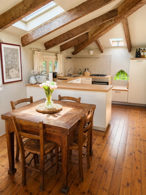 Bright kitchen with exposed wooden beams, dining table with flowers, and garden view in Garden Loft at Veneto Villa,