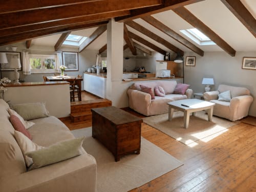 Garden Loft living area at Veneto Villa with exposed beams, cream furniture, wooden beams, skylight, kitchen, and garden