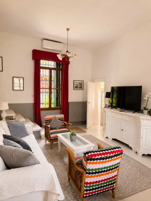 Elegant living room at Veneto Villa's Wisteria Lodge with red curtains, comfortable seating, and garden views in