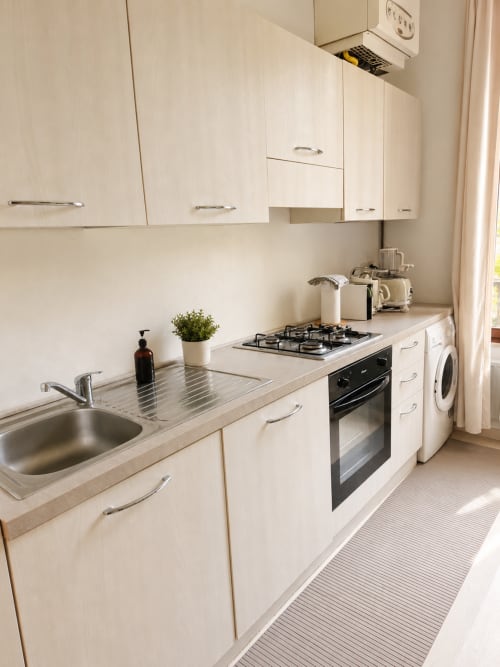 Modern kitchen in Wisteria Lodge villa at Veneto Villa with white cabinetry, gas stovetop, oven, and washing machine