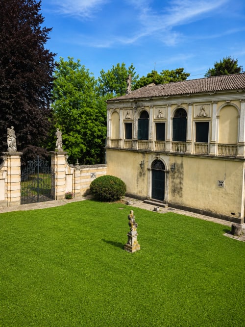 Elegant villa courtyard at Veneto Villa in Sant'Agostino with manicured green lawn, classical statues, and Renaissance-style