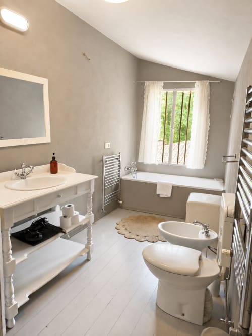 Elegant bathroom at Veneto Villa Wisteria Lodge with bathtub, dual sinks, heated towel rack, and garden view window in