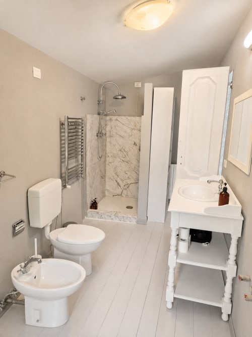 Modern bathroom at Veneto Villa's Wisteria Lodge with marble shower, dual sinks, toilet, and heated towel rack in