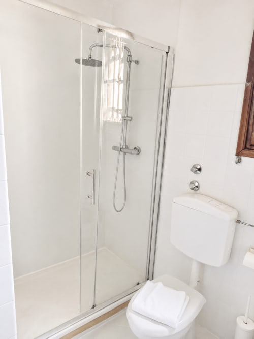 Modern bathroom in Wisteria Lodge villa at Veneto Villa with glass shower enclosure and white toilet