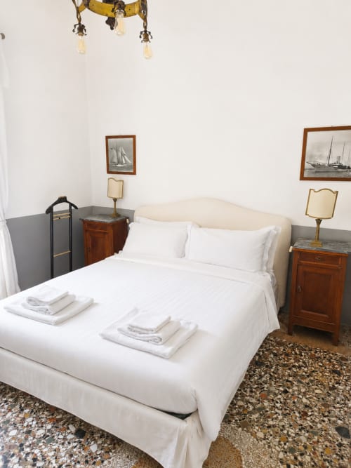 Wisteria Lodge bedroom at Veneto Villa with white bed, wooden nightstands, nautical artwork, and period furnishings