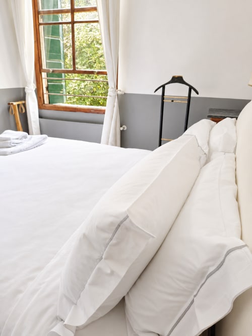 Bright bedroom at Veneto Villa with white pillows, garden view window, and black clothing rack in Wisteria Lodge