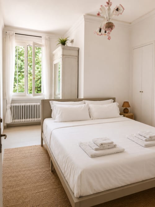 Bright bedroom at Veneto Villa's Garden Lodge in Sant'Agostino with white linens, garden view windows, and modern amenities