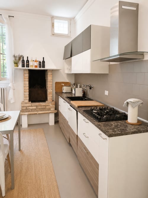 Modern kitchen in Garden Lodge apartment at Veneto Villa with gas stove, dark countertop, and fireplace view