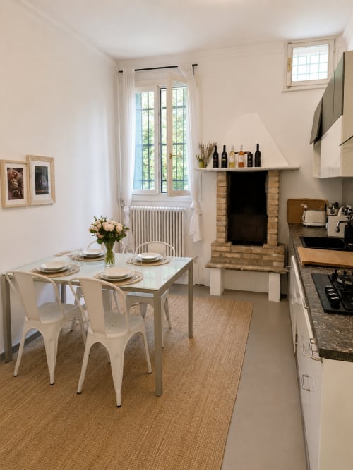 Modern kitchen-dining area in Garden Lodge apartment at Veneto Villa with fireplace, white furniture, and garden views