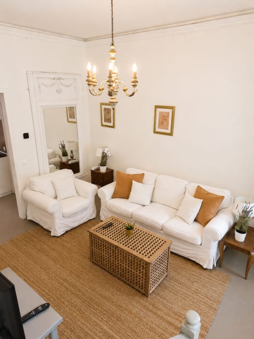 Elegant living room at Veneto Villa Garden Lodge with cream sofa, armchair, wooden coffee table, and brass chandelier in