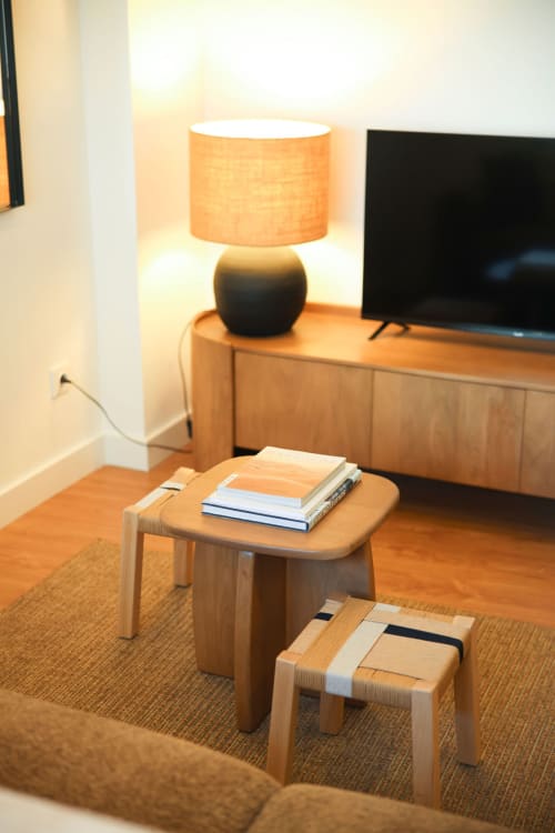 Modern living room at Sea'Ya Cascais with wooden furniture, orange table lamp, books, and flat-screen TV
