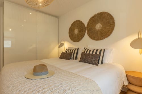 Modern bedroom at Sea'Ya Cascais villa in Portugal with coastal-inspired decor, woven wall art, and striped pillows