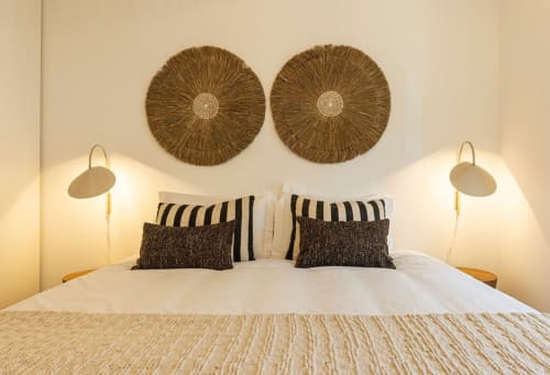 Modern bedroom at Sea'Ya Villas Cascais with white bedding, striped pillows, woven wall art, and bedside lamps with gold