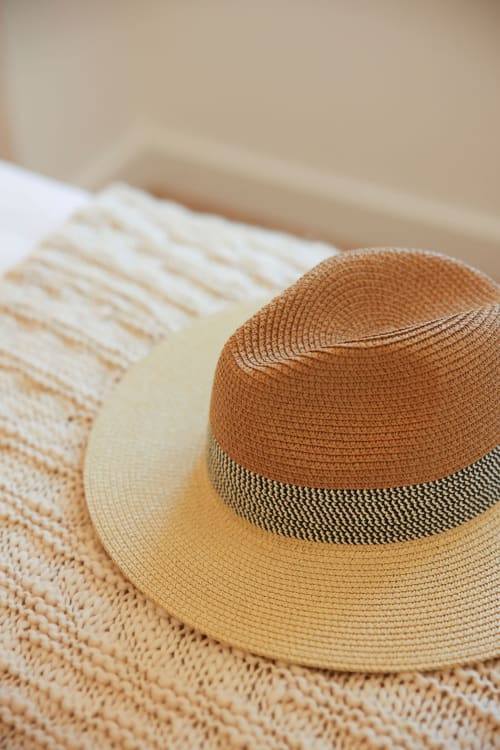 Straw hat with brown band on textured neutral fabric at Sea'Ya Cascais villa in Portugal