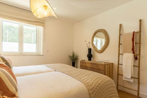 Bright modern bedroom at Sea'Ya Villas in Cascais with twin beds, rope-framed mirror, and wooden furnishings