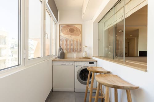 Modern laundry room in Sea'Ya Cascais apartment with washing machine, dishwasher, wooden counter, bar stools, and large