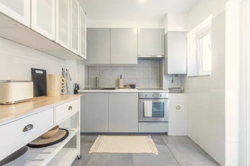 Modern white kitchen with marble backsplash, stainless steel oven, and wooden countertops at Sea'Ya Cascais apartment