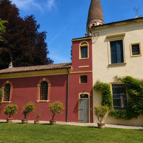 Veneto Villa in Sant'Agostino: historic red and cream villa with tall tower, manicured garden, and ivy-covered walls