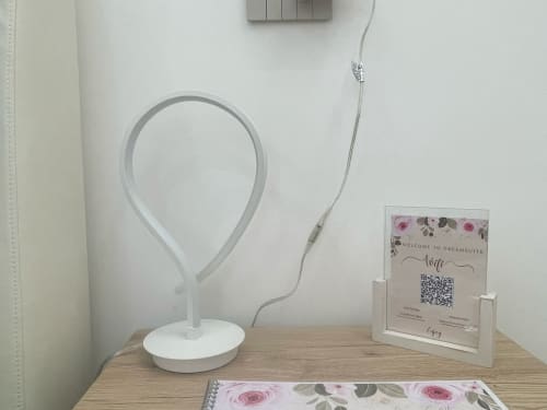 Scrivania Dream Suite Bologna con lampada da tavolo bianca, cartello di benvenuto con codice QR e taccuino con design floreale rosa