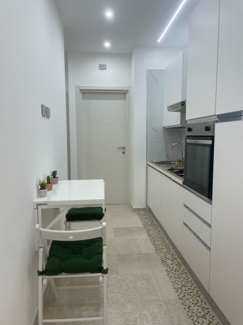 Cucina moderna bianca con zona cottura attrezzata e tavolo da pranzo nella Dream Suite Bologna