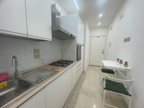 Cucina bianca moderna con piano cottura a gas, rivestimento in marmo e zona pranzo in appartamento a Bologna