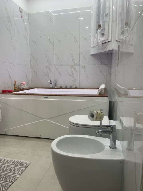Bagno moderno con piastrelle in marmo, lavabo tondo, toilet e vasca jacuzzi presso Dream Suite Bologna