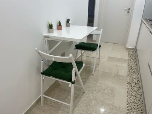 Moderna zona pranzo della Dream Suite Bologna con tavolo bianco, sedie con cuscini verdi e piante in vaso